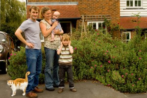 Family of parents and two sons outside their new family home - with their cat.